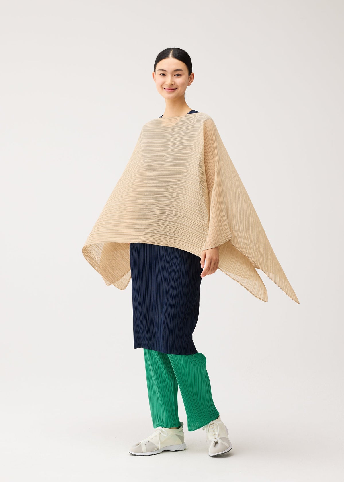 A person wears a beige COLORFUL MADAME-T SMALL pleated stole with a hole over a navy pleated dress and green pleated trousers, paired with white sneakers. view 7 of 7