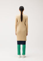 A person seen from behind wears a tan long-sleeved pleated tunic over a dark navy pleated skirt and green pleated trousers from the NEW COLORFUL BASICS 5 collection by PLEATS PLEASE ISSEY MIYAKE.