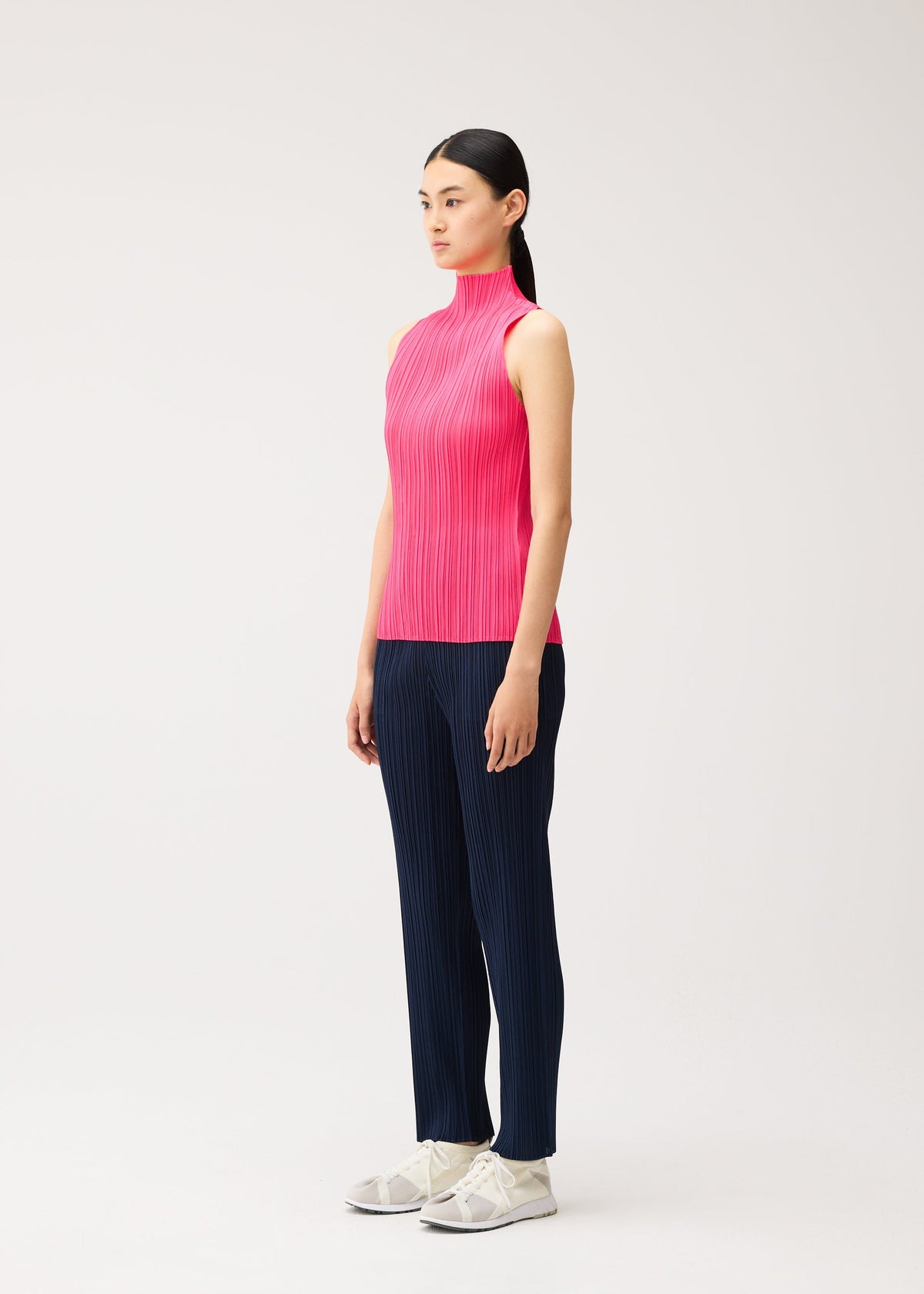 A person wearing a NEW COLORFUL BASICS 5 hot pink sleeveless mock-neck top and navy blue straight pants, both featuring vertical pleats, with white sneakers. view 8 of 10