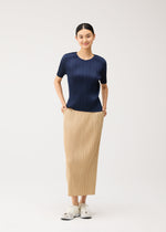 A person wearing a pleated dark blue short-sleeved top and matching pleated beige maxi skirt with pockets and light-colored sneakers from the PLEATS PLEASE ISSEY MIYAKE NEW COLORFUL BASICS 5 collection.