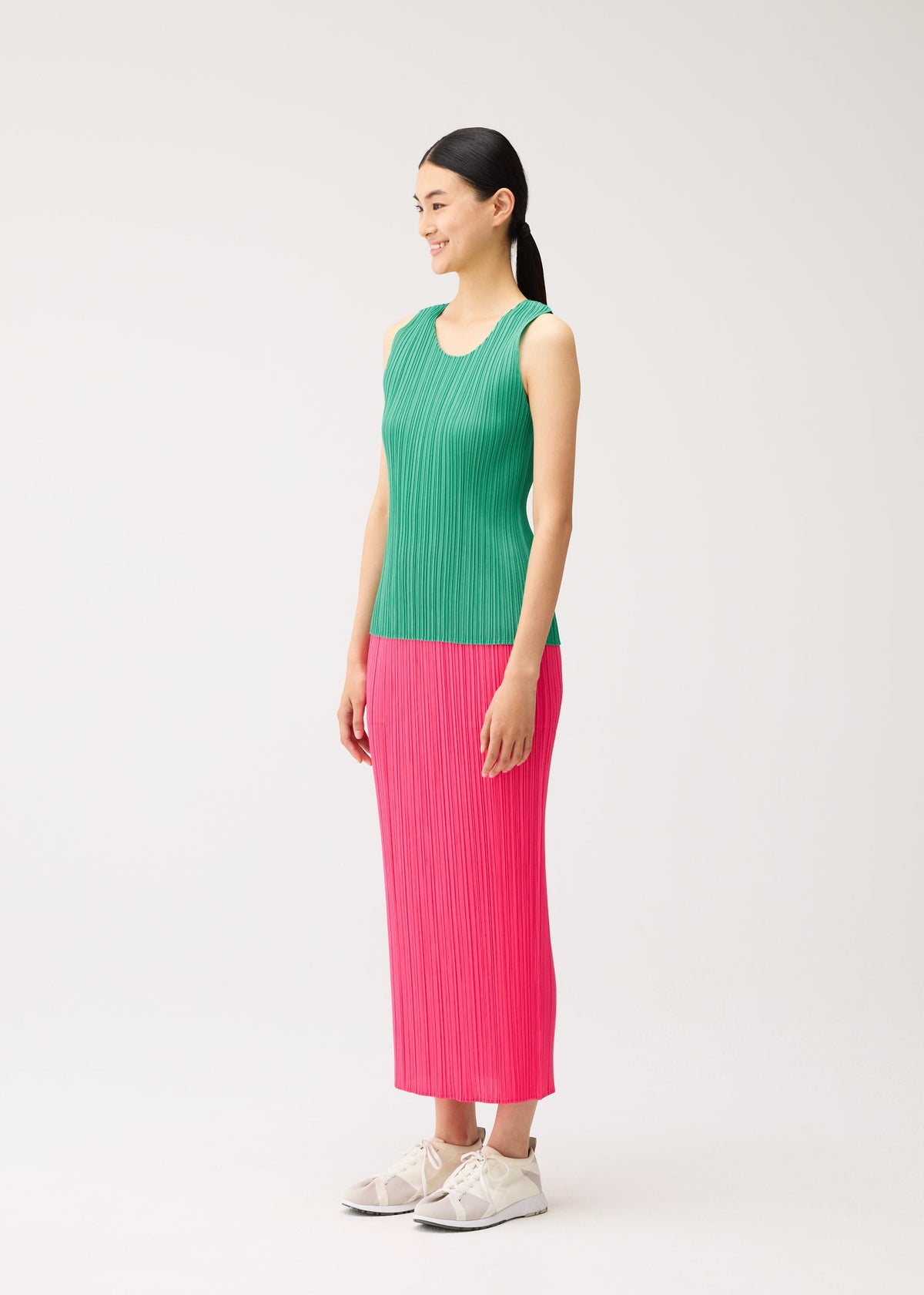 A woman wearing a NEW COLORFUL BASICS 5 round-neck sleeveless top and a long pink pleated skirt with light-colored sneakers. view 8 of 10