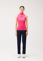 A person wearing a brightly colored, sleeveless mock-neck pleated top and dark blue pleated trousers from the NEW COLORFUL BASICS 5 collection by PLEATS PLEASE ISSEY MIYAKE, finished with white sneakers.