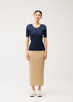 A person wears a navy blue, short-sleeved round-neck NEW COLORFUL BASICS 5 top and a long, tan pleated skirt with white sneakers.
