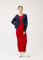 A person wearing a short, navy pleated cardigan from the NEW COLORFUL BASICS 5 collection over an easy-to-style red maxi dress and white sneakers.