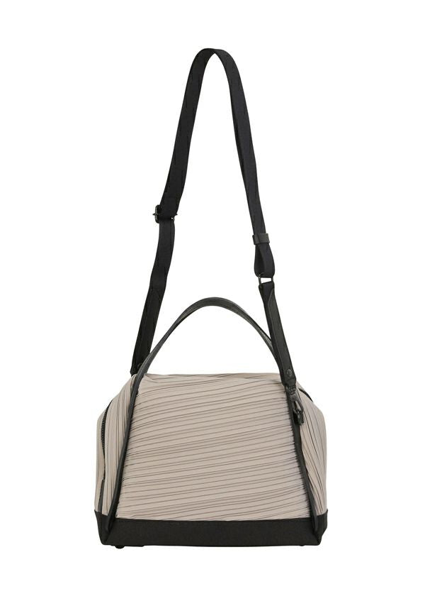 The BIAS PLEATS BAG by PLEATS PLEASE ISSEY MIYAKE is a beige and black pleated bag featuring a black top handle and adjustable shoulder strap, shown against a white background. view 4 of 8