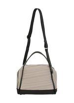 The BIAS PLEATS BAG by PLEATS PLEASE ISSEY MIYAKE is a beige and black pleated bag featuring a black top handle and adjustable shoulder strap, shown against a white background.