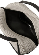 A top view of the BIAS PLEATS BAG by PLEATS PLEASE ISSEY MIYAKE shows its open beige pleated, textured exterior, black lining, visible zipper, black handles, and an attached strap for versatile shoulder bag styling.