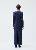 A person with braided hair faces away, wearing the TUNE long-sleeved navy tunic and matching wide-leg pants from PLEATS PLEASE ISSEY MIYAKE, paired with black shoes against a plain white background.