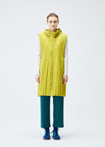A person faces forward in a PLEATS PLEASE ISSEY MIYAKE PADDED PLEATS COAT—long, sleeveless, lime green, quilted and hooded—layered over a white top, teal Keshi-pleated pants, and blue sneakers against a plain light background.