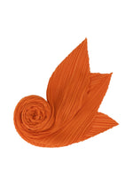 The O SCARF DECEMBER by PLEATS PLEASE ISSEY MIYAKE, in bright orange with pleats and pointed ends, is arranged in a spiral on a white background, evoking an abstract flower or bird wing.