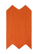The O SCARF DECEMBER by PLEATS PLEASE ISSEY MIYAKE features an orange, zigzag design with chevron patterns and pleated textures, creating a striking three-dimensional effect on a white background.