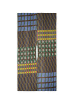 The HARMONY MADAME-T by PLEATS PLEASE ISSEY MIYAKE is a large scarf with geometric patterns in green, blue, yellow, red, and brown. It features a central vertical opening and bold stripes, triangles, and rectangles in symmetrical style. - BLUE （no.72）