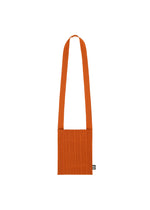 The CREPE KNIT BAG by PLEATS PLEASE ISSEY MIYAKE is an orange, pleated shoulder bag with a wide strap and a small black and white label near the bottom, displayed against a white background. - DARK ORANGE （no.33）