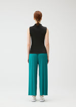 A person faces away from the camera wearing PLEATS PLEASE ISSEY MIYAKE's MIST JUNE: a high-neck sleeveless black top, teal finely pleated wide-leg pants, and white sneakers, set against a plain white background.