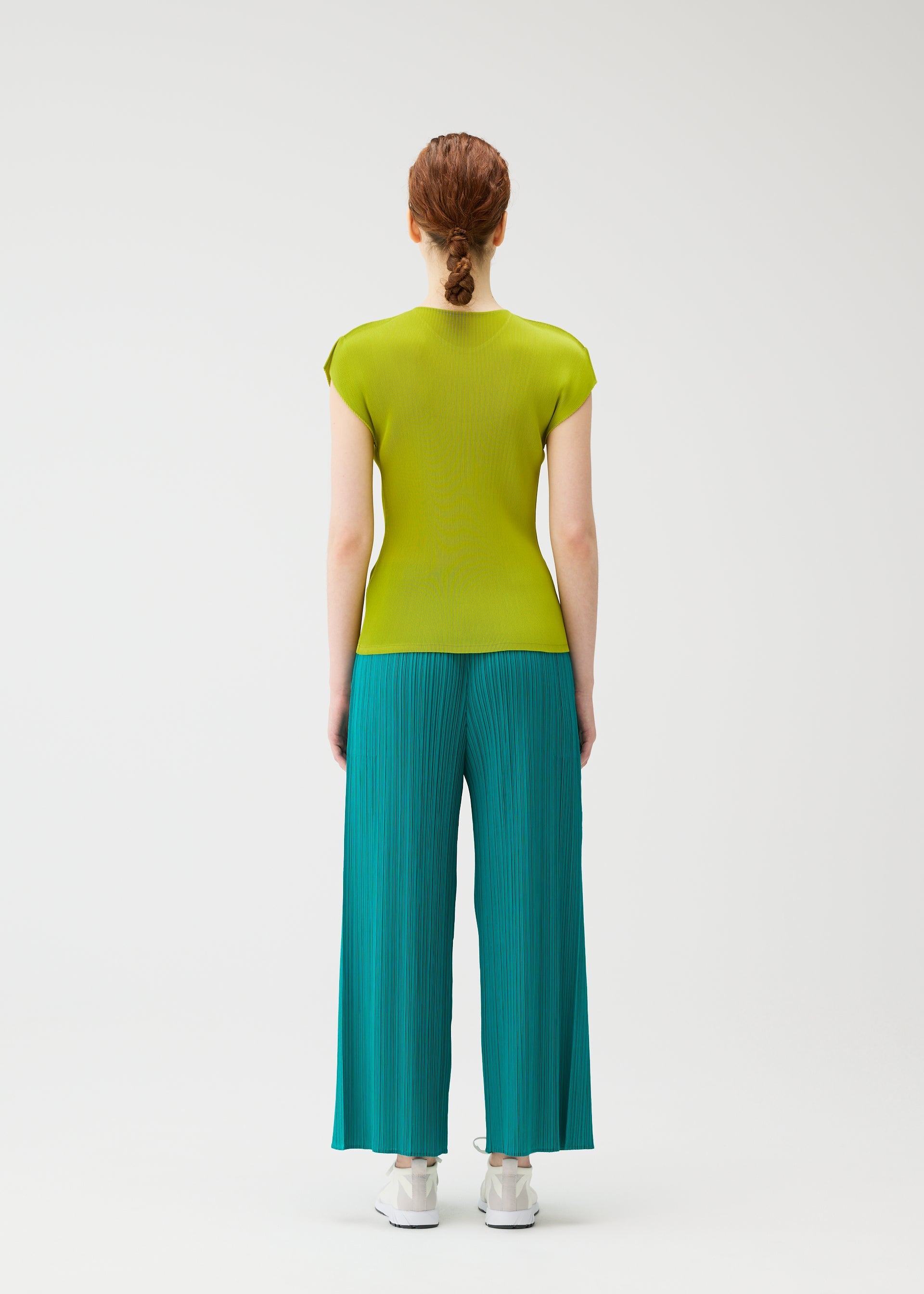 Zoomed view A person with red hair in a braid, seen from behind, wears the MIST JUNE set by PLEATS PLEASE ISSEY MIYAKE—featuring a fitted lime green round-neck top and teal finely pleated wide-leg pants—against a plain white background.