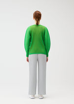 A person with red hair in a low braid, seen from behind, wears the bright green TATAMI APRIL pleated top with dolman sleeves by PLEATS PLEASE ISSEY MIYAKE and light gray wide-leg pants against a plain white background.