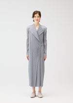 A person faces forward, wearing the FACADE long coat by PLEATS PLEASE ISSEY MIYAKE with a light gray pleated wrap and subtle cord details, paired with beige slippers, against a plain white background.