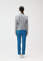 A person faces away, wearing a light gray long-sleeved pleated top and bright blue pleated pants from PLEATS PLEASE ISSEY MIYAKE's MONTHLY COLORS : FEBRUARY, paired with white shoes against a plain white background.