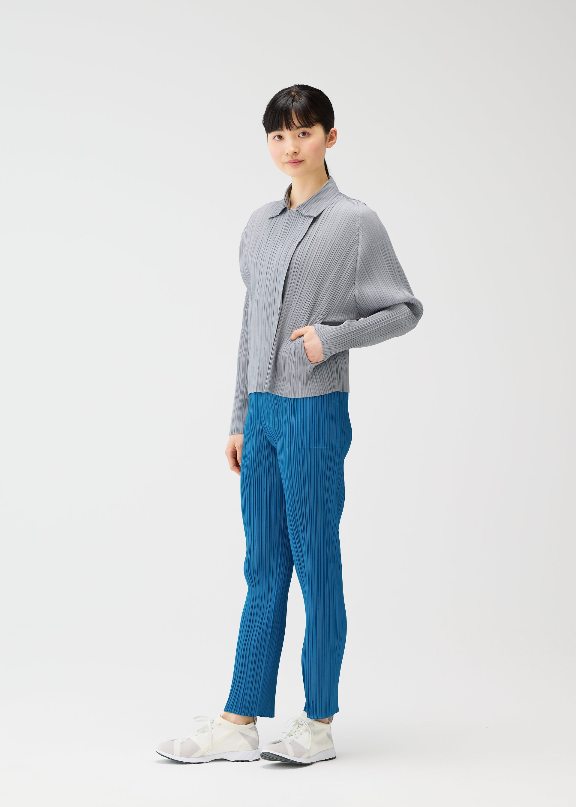 Zoomed view A woman with her hand in her pocket wears a collared jacket from PLEATS PLEASE ISSEY MIYAKE’s MONTHLY COLORS : FEBRUARY, reflecting the series’ relaxed yet polished style.