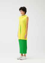 A person with short curly hair wears MONTHLY COLORS : APRIL by PLEATS PLEASE ISSEY MIYAKE— a hooded long vest over a sleeveless pleated yellow top and green pleated dress, paired with white sneakers against a plain white background.