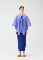 A woman with short hair and beige platform sandals stands against a white background, wearing the LUCID PLEATS dress and a 3D light blue pleated shawl by PLEATS PLEASE ISSEY MIYAKE, looking forward with a neutral expression.