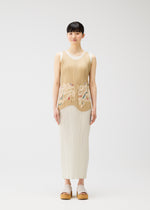 A woman stands against a white background, wearing the I SPY! sleeveless pleated dress with embroidered seashells by PLEATS PLEASE ISSEY MIYAKE and white platform sandals, looking straight ahead with a neutral expression.