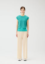 A person stands facing forward against a plain white background, wearing LOOP BOTTOMS by PLEATS PLEASE ISSEY MIYAKE: cream wide-leg straight pants made from recycled polyester, paired with a turquoise top and white sneakers.