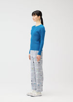 A woman in profile poses against a white background, dressed in the CROSSING DOTS pants from PLEATS PLEASE ISSEY MIYAKE, paired with a blue ribbed long-sleeve top and white shoes adorned with bows.