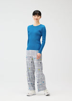 A woman stands against a plain white background wearing the CROSSING DOTS wide-leg straight pants by PLEATS PLEASE ISSEY MIYAKE, featuring a plaid and dots pattern, paired with a bright blue ribbed top and white sneakers.
