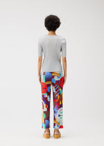 Facing away, a person with short curly hair wears the PLAYGROUND ribbed top and colorful geometric pants by PLEATS PLEASE ISSEY MIYAKE, styled with tan platform sandals against a plain white background.