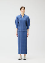 A woman with light skin and brown hair tied back wears the PLEATS PLEASE ISSEY MIYAKE COTTON DENIM set—an ocean breeze blue, textured ribbed top with three-quarter sleeves and a matching denim-inspired skirt—against a plain white background.