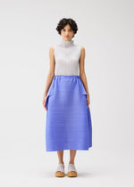 A woman with short curly hair models the BOUNCY BASKET blue pleated skirt with large pockets and a sleeveless white top by PLEATS PLEASE ISSEY MIYAKE, standing against a plain white background for an elegant, timeless look.