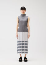 A woman with straight dark hair and bangs wears the PLEATS PLEASE ISSEY MIYAKE BUMPY BASKET dress, featuring a sleeveless, high-neck gray pleated top, white midsection, striped gray and white skirt with pockets, and black platform sandals.
