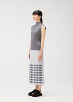 A woman stands sideways against a plain white background, wearing the PLEATS PLEASE ISSEY MIYAKE BUMPY BASKET sleeveless gray and white long dress with pleated texture, striped hem, and black platform sandals.