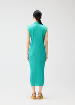 A person with long dark hair in a low ponytail stands facing away, wearing a sleeveless teal pleated dress from PLEATS PLEASE ISSEY MIYAKE's MONTHLY COLORS: MAY and tan platform sandals. The background is plain white.