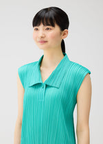 A young woman with straight black hair in a ponytail wears the PLEATS PLEASE ISSEY MIYAKE MONTHLY COLORS : MAY sleeveless dress with a pleated teal top, standing against a plain light background and smiling gently to the side.