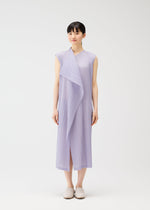 Someone stands against a white background in the PLEATS PLEASE ISSEY MIYAKE RAMIE PLEATS sleeveless light purple dress with pleats and a draped front, paired with white slip-on shoes. They have short dark hair and a neutral expression.