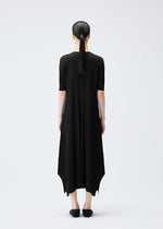 A woman with straight dark hair in a low ponytail stands facing away in the black, pleated MELLOW PLEATS dress by PLEATS PLEASE ISSEY MIYAKE, paired with black shoes, against a plain white background.