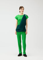A woman with short brown hair smiles slightly as she models the SWING set by PLEATS PLEASE ISSEY MIYAKE: a bright green pleated French-sleeve top and pants, paired with a dark green pleated scarf draped diagonally, against a plain white background.