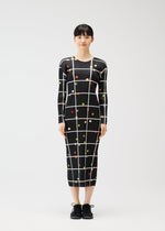 A woman faces forward wearing the PLEATS PLEASE ISSEY MIYAKE CROSSING DOTS dress, a long-sleeved, form-fitting round-neck style with a black base, white grid pattern, and colorful dots. She has straight black hair and wears black shoes against a white background.