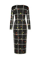 CROSSING DOTS by PLEATS PLEASE ISSEY MIYAKE: a black, long-sleeved dress with a round neck, white grid pattern, and scattered multicolored dots in yellow, red, and orange. Shown on a plain white background.