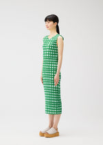 A woman stands in profile wearing the PLEATS PLEASE ISSEY MIYAKE BASKET green and white block check print sleeveless dress with beige platform sandals against a plain white background.