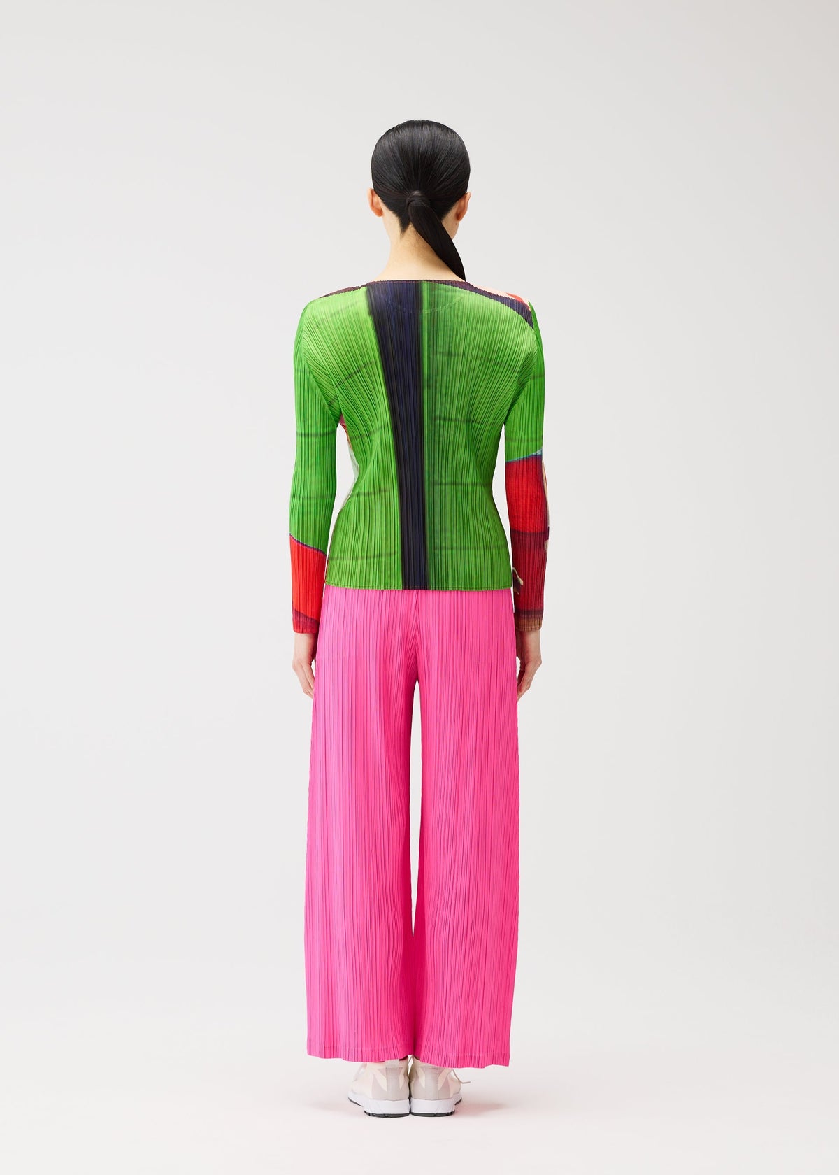 A person with long black hair in a low ponytail wears the CITY COLLAGE top and bright pink pleated pants by PLEATS PLEASE ISSEY MIYAKE, standing facing away against a plain background. view 7 of 7