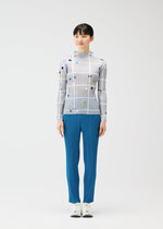 A person stands facing forward against a plain white background, wearing the CROSSING DOTS sheer white grid-patterned top with colored dots and blue pleated pants by PLEATS PLEASE ISSEY MIYAKE, paired with white shoes.