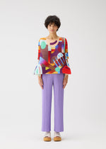 A person with short curly hair stands against a white background wearing PLEATS PLEASE ISSEY MIYAKE's PLAYGROUND geometric-print round-neck top with flared sleeves, lilac pleated pants, and platform sandals.