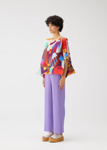 A person stands in profile against a white background, wearing the PLAYGROUND top by PLEATS PLEASE ISSEY MIYAKE, loose lavender pleated pants, beige platform sandals, and light socks.