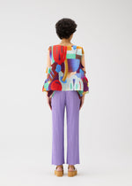 A person with short curly hair faces away, wearing the PLAYGROUND elbow-sleeved top and lilac pleated pants by PLEATS PLEASE ISSEY MIYAKE, paired with tan platform sandals against a plain white background.