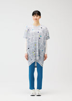 A person faces the camera wearing the PLEATS PLEASE ISSEY MIYAKE CROSSING DOTS tunic over a long-sleeve white top, blue pleated pants, and white sneakers, against a plain white background.