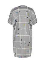 The CROSSING DOTS tunic by PLEATS PLEASE ISSEY MIYAKE is a knee-length, short-sleeve, loose-fit style featuring a gray base with plaid stripes and multicolored dots in blue, yellow, green, and black.