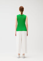 A woman with red hair in a braid wears PLEATS PLEASE ISSEY MIYAKE A-POC BOTTOMS and a sleeveless green top, standing facing away against a plain white background.